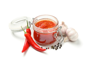 Tasty chili sauce in glass jar and ingredients isolated on white background