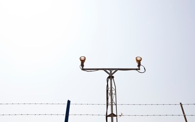 Lighting equipment at the start of airport runway surrounded by barb wire