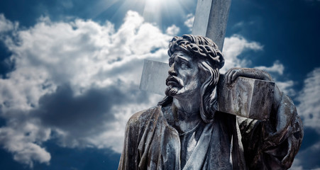  Ancient statue of Jesus Christ with cross. Pain, suffering and resurrection concept.