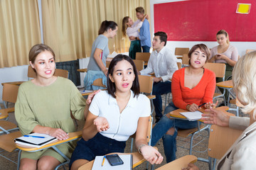 Friendly student group talking in classroom having break between lessons