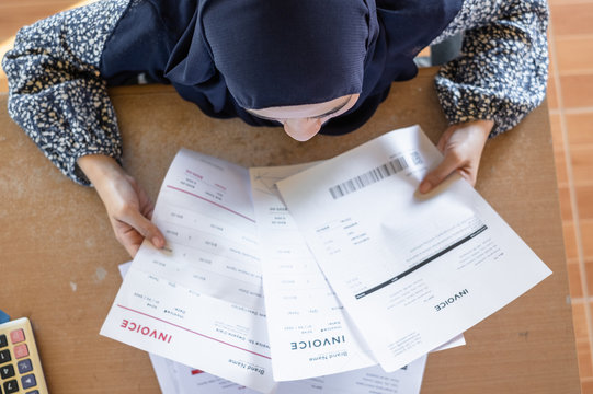 Top view of Muslim woman wearing hijab reading the invoice documents.