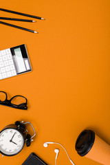 School and office supplies lie neatly on an orange background