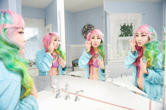 Young Woman Applying Makeup With Multiple Mirror Reflections