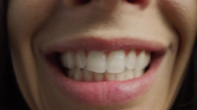 Close Up Macro Shot of a Mouth with Perfect White Teeth. Person Talks and We See the Mouth and Tongue Movements. Woman with Beatiful Natural Healthy Red Lips and Even Teeth with Pretty Smile.