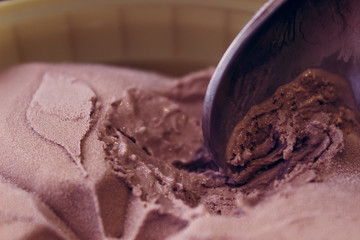 A bucket of chocolate ice cream with a spoon. Spoon took the ice cream with the taste of chocolate. Beautiful ice cream pattern.