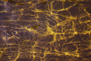 Abstract gold reflection in water moving wave with sunlight.
