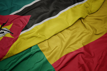 waving colorful flag of benin and national flag of mozambique.