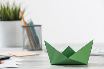 Wooden office desk with green origami boat.