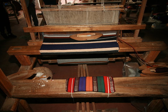 Old fashioned loom with woven blanket in progress