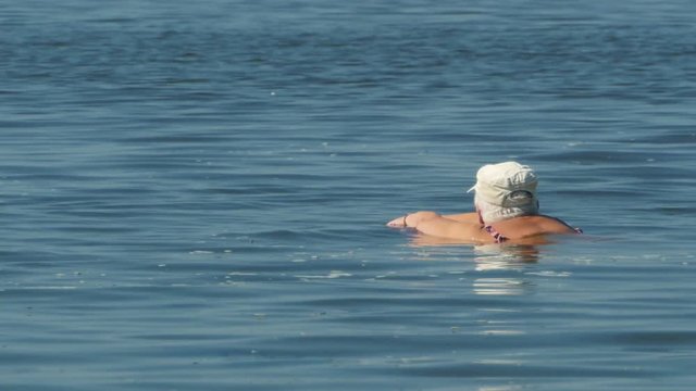 Unrecognizable Elderly Woman Swimming In The Water On The Beach