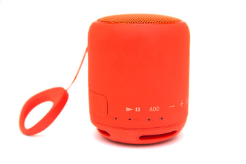 Small red portable wireless music speaker isolated over white background. Music outdoors. Hobby and leisure concept. Music addiction. Selective focus