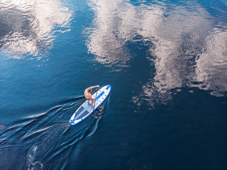 Man rowing oar on sup board blue sea water. Aerial top view paddleboard