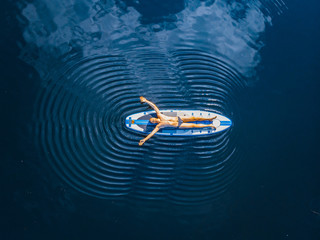 Man lying relax on sup board blue sea water. Aerial top view paddleboard