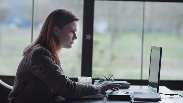 problems in business, a young woman entrepreneur is nervous working remotely slams a laptop while sitting at a table by window in cafe