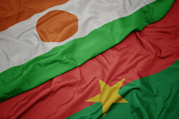 Obraz premium waving colorful flag of burkina faso and national flag of niger.