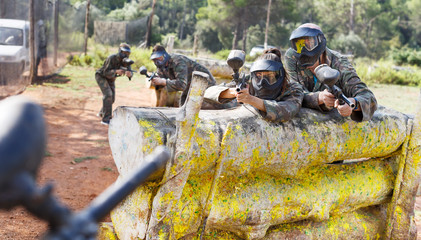 Paintball players aiming and shooting with guns