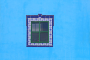 Blue ceramic mosaic window frame in turquoise wall