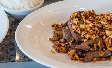 Fried liver with deep fried garlic on top. Asian cuisine serving on table.