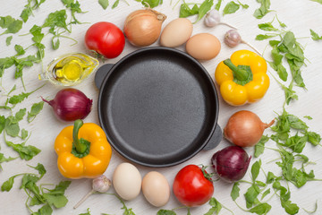 Frying pan. A set of vegetables for a healthy diet, yellow and red peppers, tomatoes, onions, garlic and spinach. Top view.