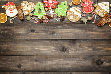 Christmas gingerbread cookies with cinnamon, candies and sugar cubes on brown wooden table