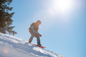 Snowboarder Riding Snowboard in Mountains at Sunny Day. Snowboarding and Winter Sports