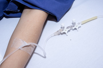 A saline tube for patient in the hospital.Close up of saline drip in patient's hand . Asian woman with hospital admission, Copy space