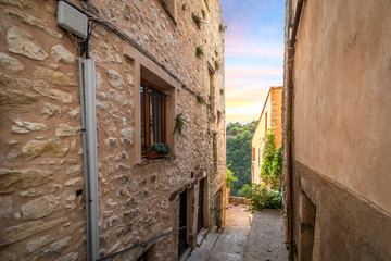Fototapeta na wymiar Sunset and mountain view through an alley in the medieval stone village of Tourrettes Sur Loup in the south of France.