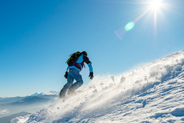 Naklejka na ściany i meble Snowboarder Riding Snowboard in Mountains at Sunny Day. Snowboarding and Winter Sports