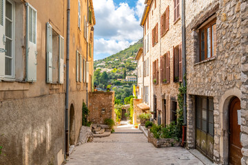 Fototapeta na wymiar The Alpes-Maritimes mountains and towns of Southern France are visible from a medieval street in Tourrettes Sur Loup, France, on the French Riviera