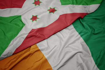 waving colorful flag of cote divoire and national flag of burundi .