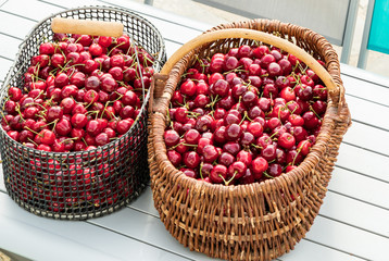 two baskets filled with beautiful red cherries on a garden table