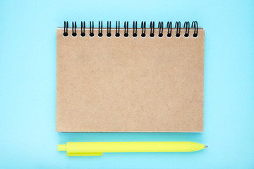 Blank notepad with pen on blue background