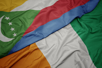 waving colorful flag of cote divoire and national flag of comoros.