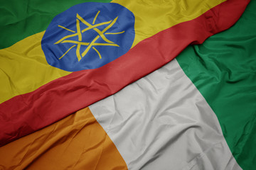 waving colorful flag of cote divoire and national flag of ethiopia .