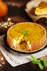 Cheese cake with passion fruit on a dark background. Cheese cake with passion fruit sauce on top, decorated with mint