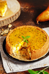 Cheese cake with passion fruit on a dark background. Cheese cake with passion fruit sauce on top, decorated with mint