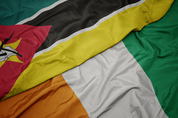 waving colorful flag of cote divoire and national flag of mozambique.