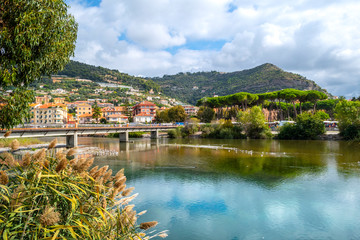 The bridge over the River Roia, filled with seagulls and ducks with the Italian village of Ventimiglia behind on the Italian Riviera.
