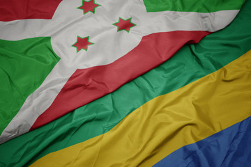 waving colorful flag of gabon and national flag of burundi .