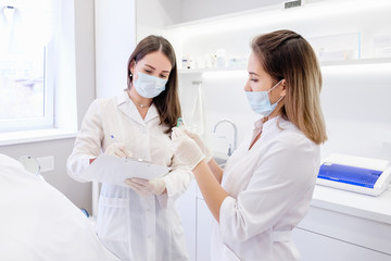 Two young pretty lab workers women examine record test data to create new effective anti-aging treatment. Technology Innovation Concept. DNA analysis Determination of paternity or family relationship