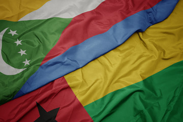 waving colorful flag of guinea bissau and national flag of comoros.