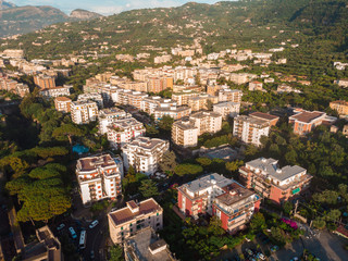 Fototapeta premium Aerial view on the Sorrento city streets, sunset, houses and Hotels, mountains and buildings in the distance. Travel and vacation concept on Italy. Infrastructure, cars and parking place