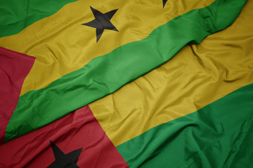 waving colorful flag of guinea bissau and national flag of sao tome and principe .