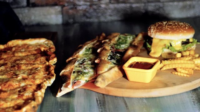 Food. Burger, small pizza cut into pieces, sauce and fries collected on the table