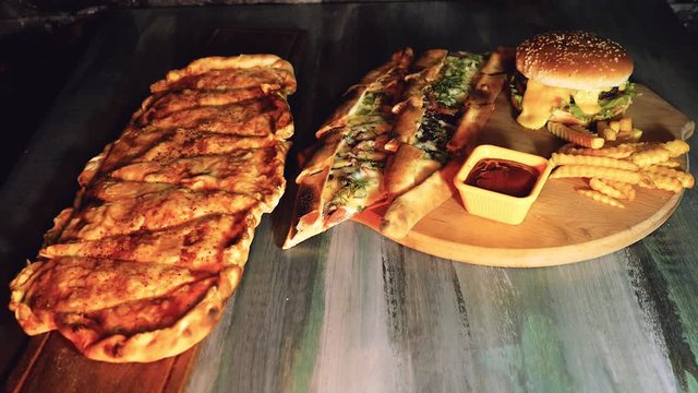 Food. Burger, small pizza cut into pieces, sauce and fries collected on the table