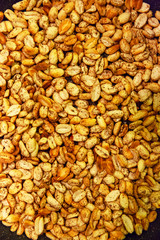 Roasted peanuts shades of yellow and brown, sprinkled with pepper appetizing appearance lies in the kitchen on a black pan.
