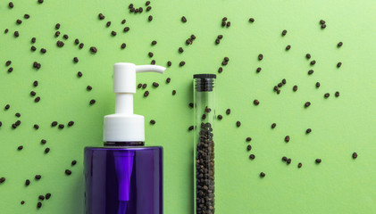 Babchi seeds in glass tube and cosmetics bottle on green background, bakuchiol ingredient.