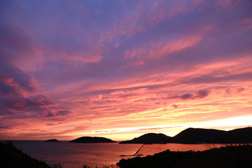 Sun setting over the sea with red and blue clouds. Gulf of La Spezia, Mediterranean Sea in Liguria.