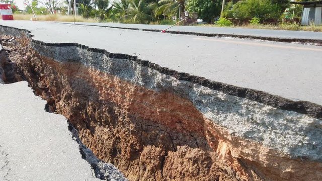Asphalt road collapsed and fallen. Road collapses with huge cracks.
