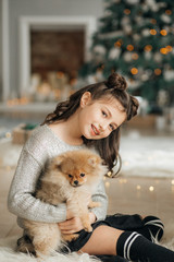 Happy little girl with dog in Christmas decorations